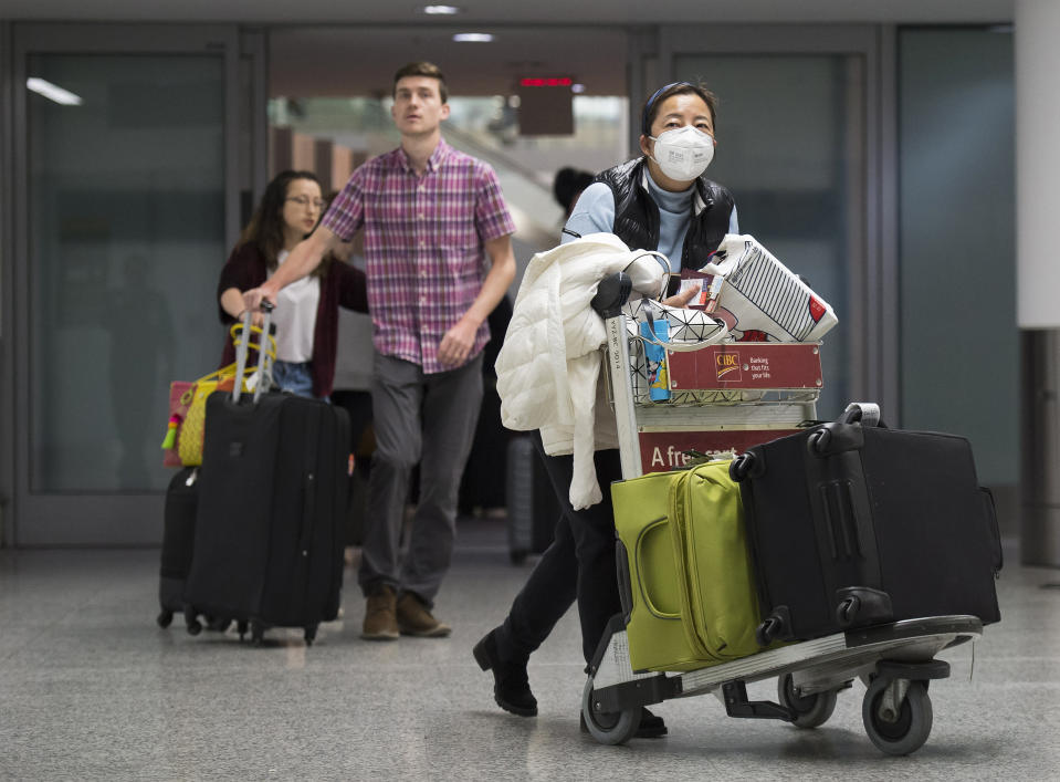 Una mujer con mascarilla camina en la zona de llegadas de la terminal internacional del aeropuerto Toronto Pearson en Toronto, Canadá, el sábado 25 de enero de 2020. (Nathan Denette/The Canadian Press via AP)