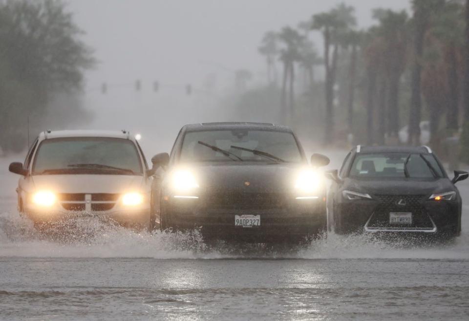 Vehicles drive along a flooded street in Palm Springs, California, as Tropical Storm Hilary approaches the area.
