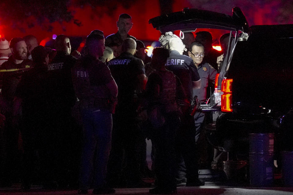 Harris County Sheriff Ed Gonzalez, facing camera at right, works with law enforcement officers from multiple agencies at the scene where a shooting suspect was barricaded in a home Thursday, Aug. 17, 2023, in Humble, Texas. The standoff ensued after two law enforcement officers were shot Thursday evening while confronting a person of interest in connection with Wednesday night's shooting of a Harris County sheriff's deputy during a traffic stop, Gonzalez said. (Brett Coomer/Houston Chronicle via AP)