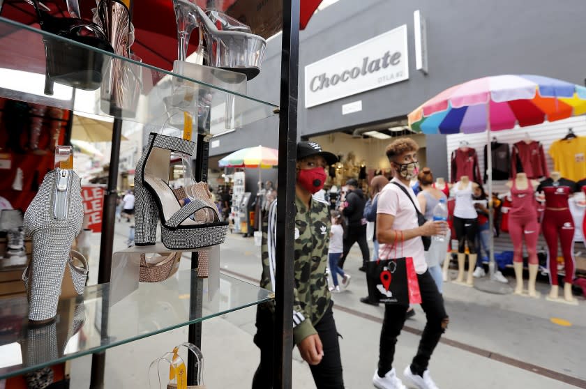 LOS ANGELES, CALIF. - JUNE 25, 2020. Shoppers wearing protective masks stroll through Santee Alley in the Los Angeles downtown garment district on Thursday, June 25, 2020. (Luis Sinco/Los Angeles Times)