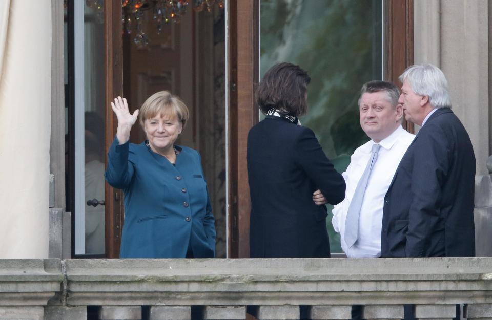 German Chancellor Merkel waves from a balcony while taking break during preliminary coalition talks in Berlin