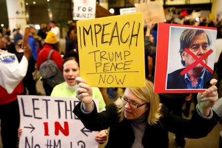 A woman holds signs against Steve Bannon and encouraging the impeachment of Trump and Pence during a protest of Donald Trump's travel ban from Muslim majority countries at the International terminal at Los Angeles International Airport (LAX) in Los Angeles, California, U.S., January 28, 2017. REUTERS/Patrick T. Fallon