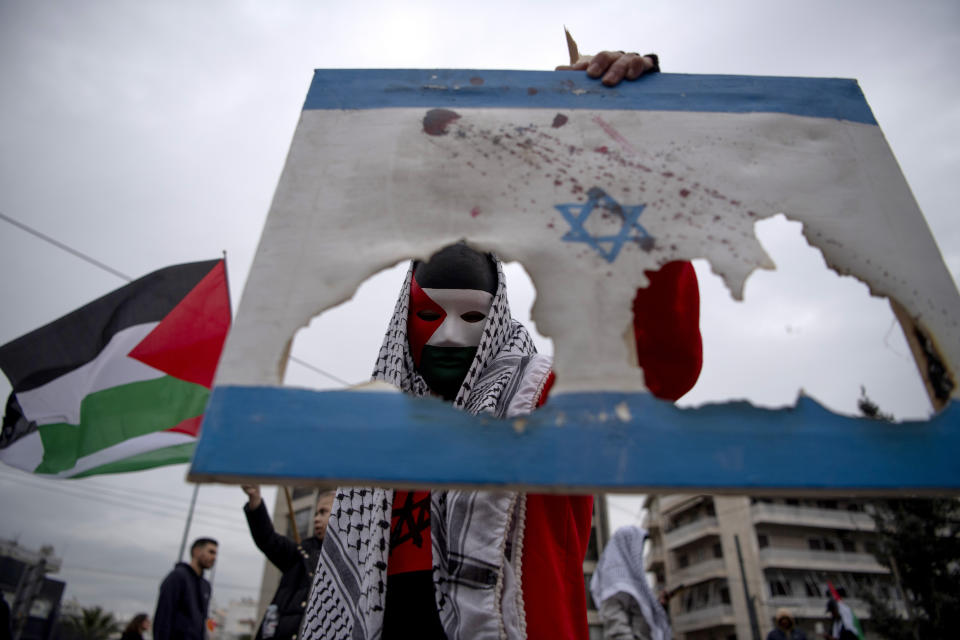 A man holds a burned Israeli flag, during a protest in front of the Israeli Embassy in Athens, Greece, Saturday, Jan. 27, 2024. Around 3,000 people staged a protest march early Saturday afternoon against the continuing Israeli military operations in Gaza. (AP Photo/Michael Varaklas)