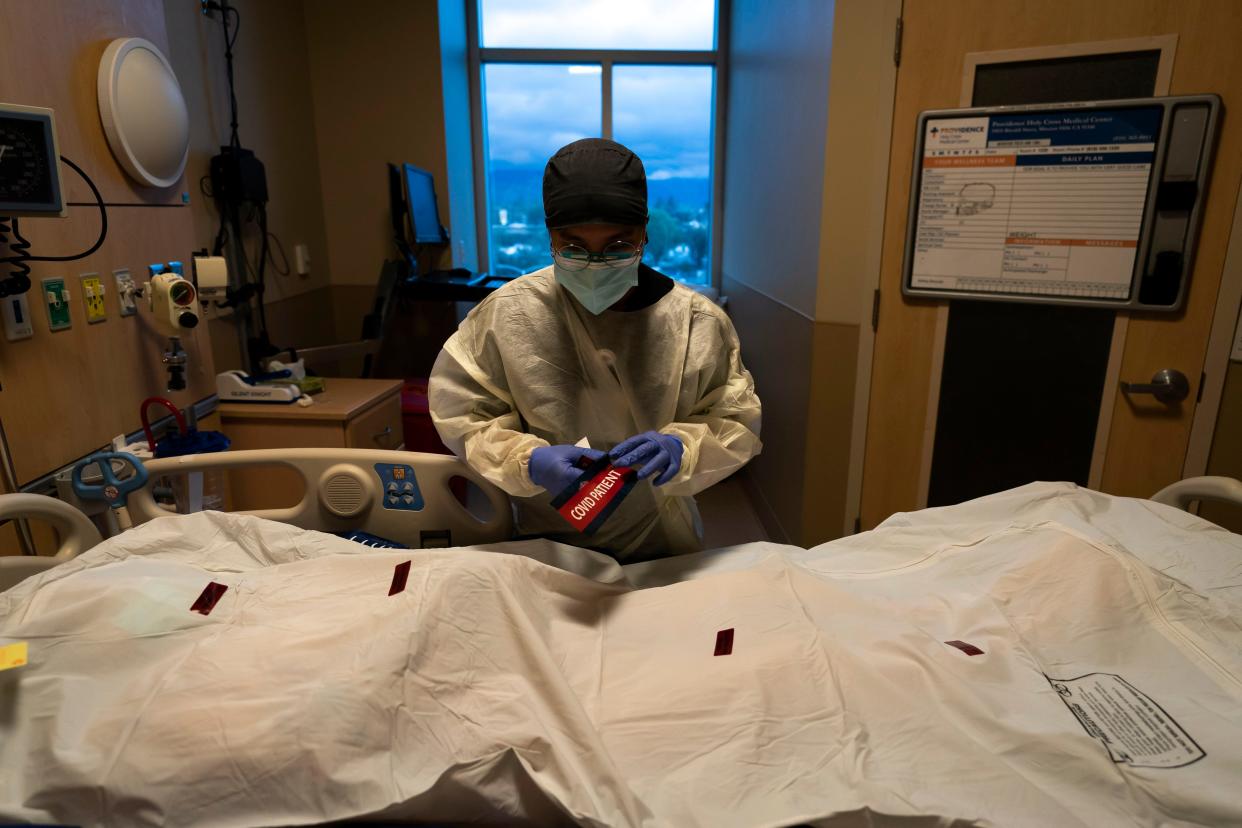 Registered nurse Bryan Hofilena attaches a "COVID Patient" sticker on a body bag of a patient who died of coronavirus at Providence Holy Cross Medical Center in Los Angeles, on Dec. 14, 2021.