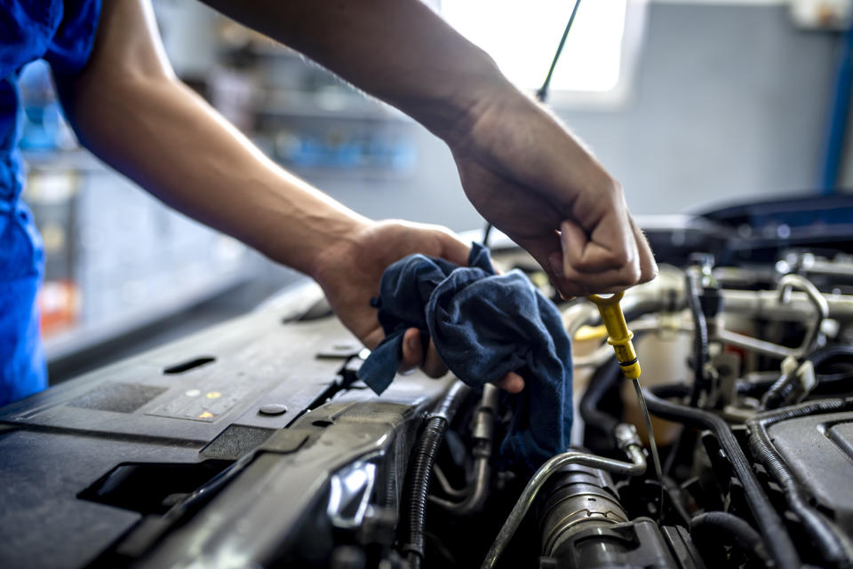 Photo of Unrecognizable male mechanic measuring the oil level of an engine at an auto shop. Mechanic checking the oil level in a car service garage. Repairing engine at a service station. Car repair."r"n.