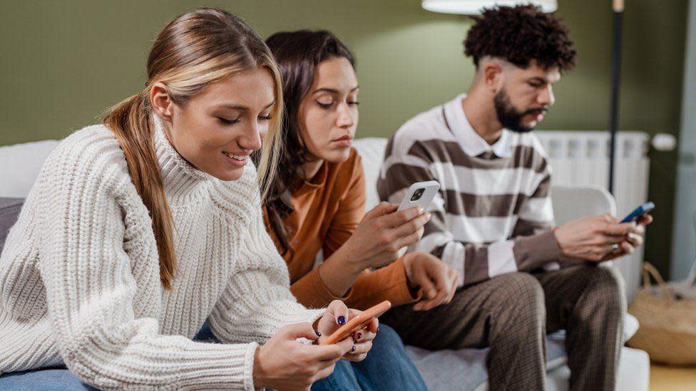 Grupo de jóvenes miran su teléfono inteligente.