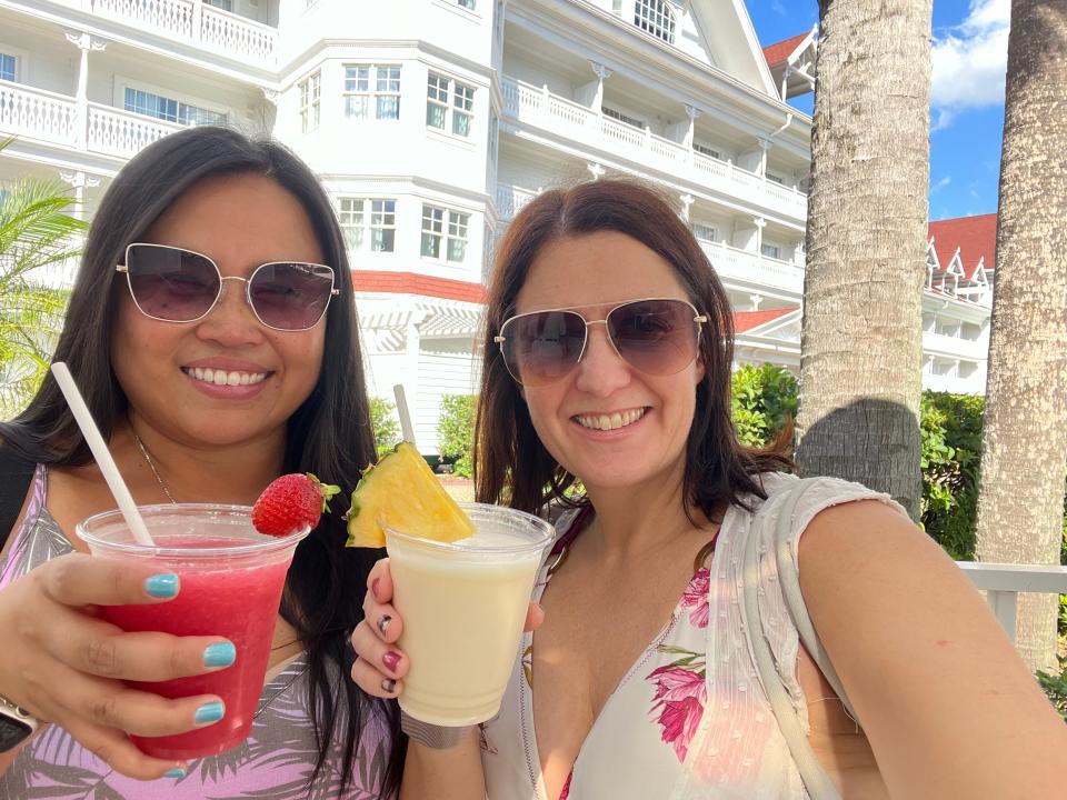 kari and her friend holding up frozen cocktails at the pool at the grand floridian in disney world