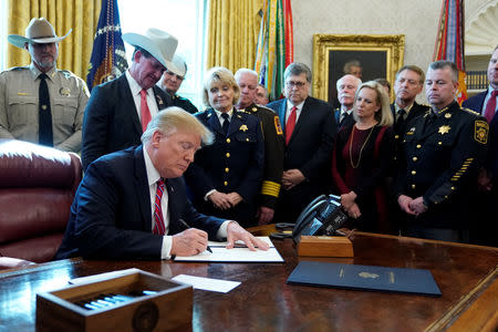 President Donald Trump signs his veto of the congressional resolution to end his emergency declaration to get funds for a border wall during a ceremony in the Oval Office of the White House in Washington, U.S., March 15, 2019. REUTERS/Jonathan Ernst