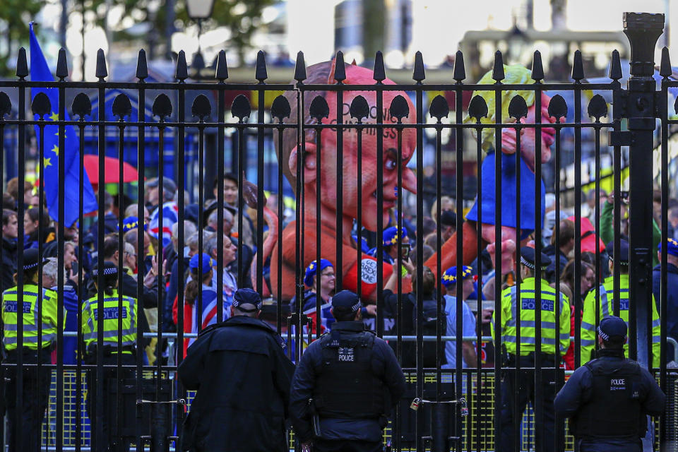 Police officers watch as anti-Brexit protestors carry effigies of British Prime Minister Boris Johnson, right, and his top advisor Dominic Cummings, left, during a march in London, Saturday, Oct. 19, 2019. In a major blow to British Prime Minister Boris Johnson, U.K. lawmakers voted Saturday to postpone a decision on whether to back his Brexit deal with the European Union, throwing a wrench into government plans to leave the bloc at the end of this month. (AP Photo/Vudi Xhymshiti)