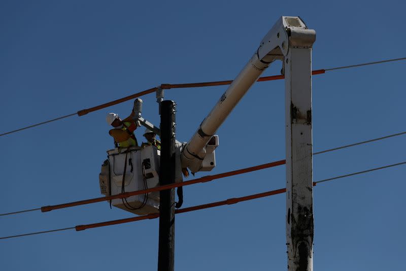 FILE PHOTO: Workers install a utility pole to support power lines after an unprecedented winter storm in Houston, Texas