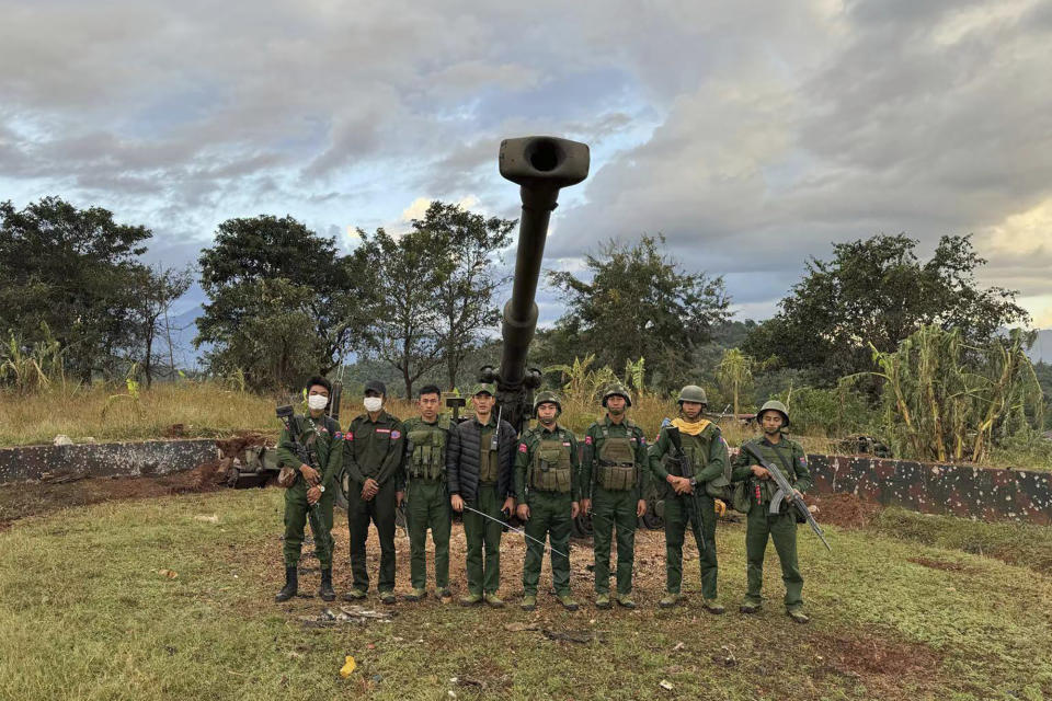In this photo provided by the Kokang online media, members of an ethnic armed forces group, one of the three militias known as the Three Brotherhood Alliance, pose for a photograph in front of weapons the group allegedly seized from Myanmar's army outpost on a hill in Hsenwi township in Shan state, Myanmar, on Nov. 24, 2023. A major offensive against Myanmar's military-run government by an alliance of three militias of ethnic minorities has been moving at lightning speed, inspiring resistance forces around the country to attack. (The Kokang online media via AP)