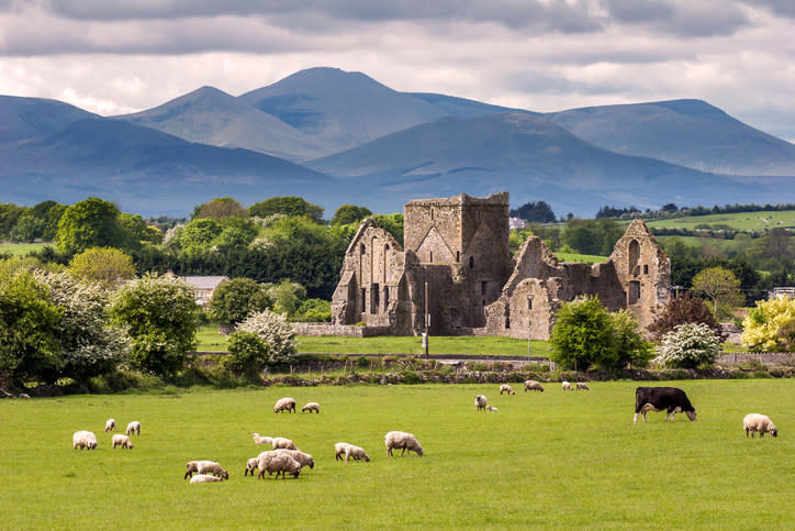 a stone structure sitting in front of fields of grass with animals grazing on them