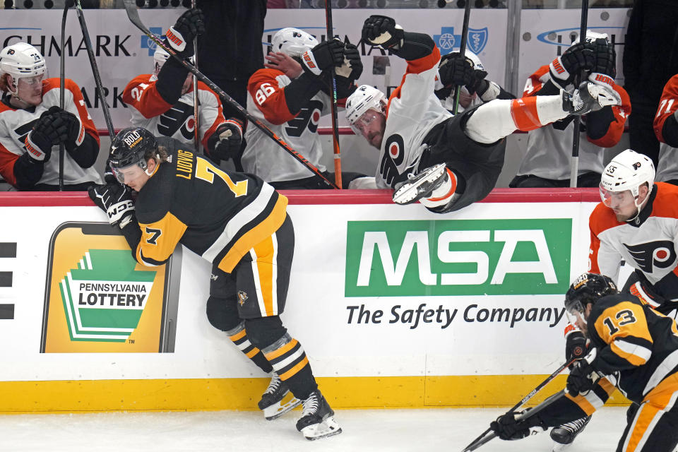 Philadelphia Flyers' Nicolas Deslauriers, top right, falls into his team's bench after colliding with Pittsburgh Penguins' John Ludvig (7) during the first period of an NHL hockey game in Pittsburgh, Saturday, Dec. 2, 2023. (AP Photo/Gene J. Puskar)