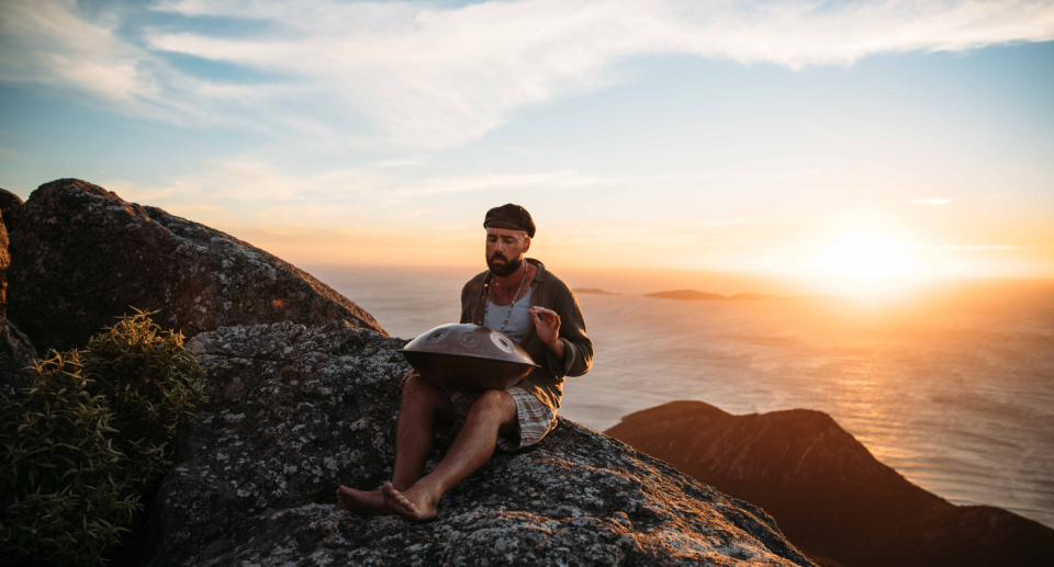 Daniel Byrne sits on a rock near the ocean.