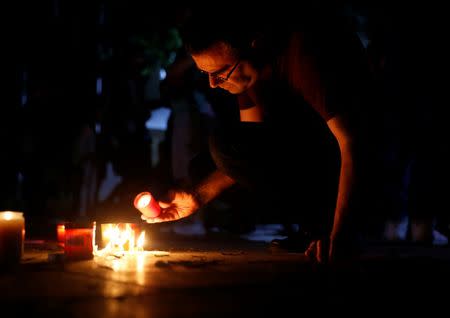 A man places a candle on the ground during a silent candlelight vigil to protest against the assassination of investigative journalist Daphne Caruana Galizia in a car bomb attack two days ago, at the University of Malta in Msida, Malta, October 18, 2017. REUTERS/Darrin Zammit Lupi