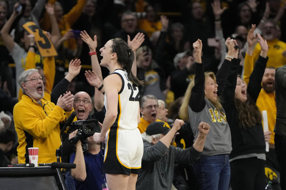 Fans applaud Iowa guard Caitlin Clark (22) after she broke the NCAA women's career scoring record during the first half of the team's college basketball game against Michigan on Thursday, Feb. 15, 2024, in Iowa City, Iowa. (AP Photo/Matthew Putney)