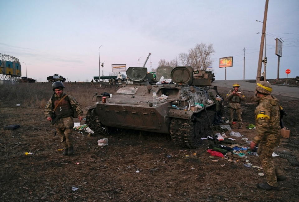 Ukrainian servicemen are seen next to a destroyed armoured vehicle, which they said belongs to the Russian army, outside Kharkiv, Ukraine February 24, 2022. REUTERS/Maksim Levin     TPX IMAGES OF THE DAY