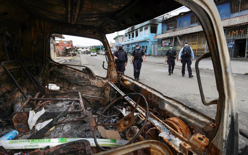 Australian peacekeepers inspect the aftermath of violent riots - Gary Ramage/AP