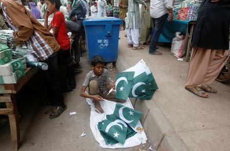 A boy counts hand flags before putting them on sale at a market ahead of Independence day in Karachi, Pakistan July 29, 2017. REUTERS/Akhtar Soomro