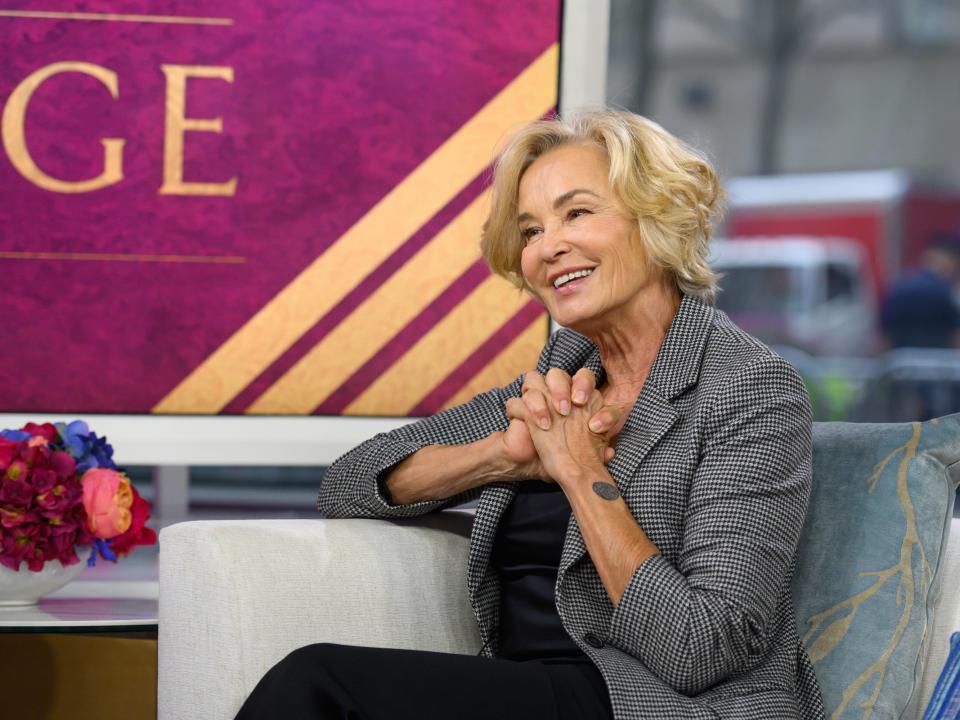 Jessica Lange in 2019 sitting on a couch and clasping her hands