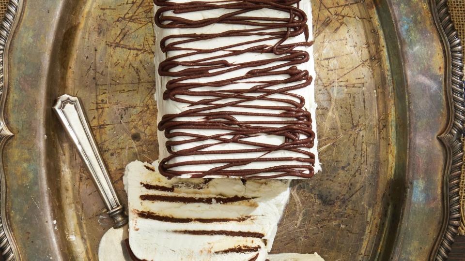 zebra semifreddo covered in whipped cream and drizzled with chocolate on a metal serving tray with a cake server