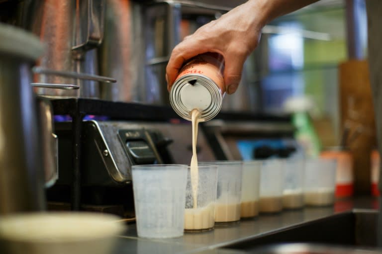 A tea master pours evaporated milk into cups as he prepares milk tea, or "lai cha", for customers at a tea shop in Hong Kong's Central district on August 10, 2016