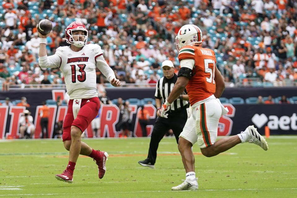 Louisville quarterback Jack Plummer (13) scrambles as he looks for a teammate under pressure from Miami linebacker Francisco Mauigoa (51) during the first half of an NCAA college football game, Saturday, Nov. 18, 2023, in Miami Gardens, Fla. (AP Photo/Wilfredo Lee)