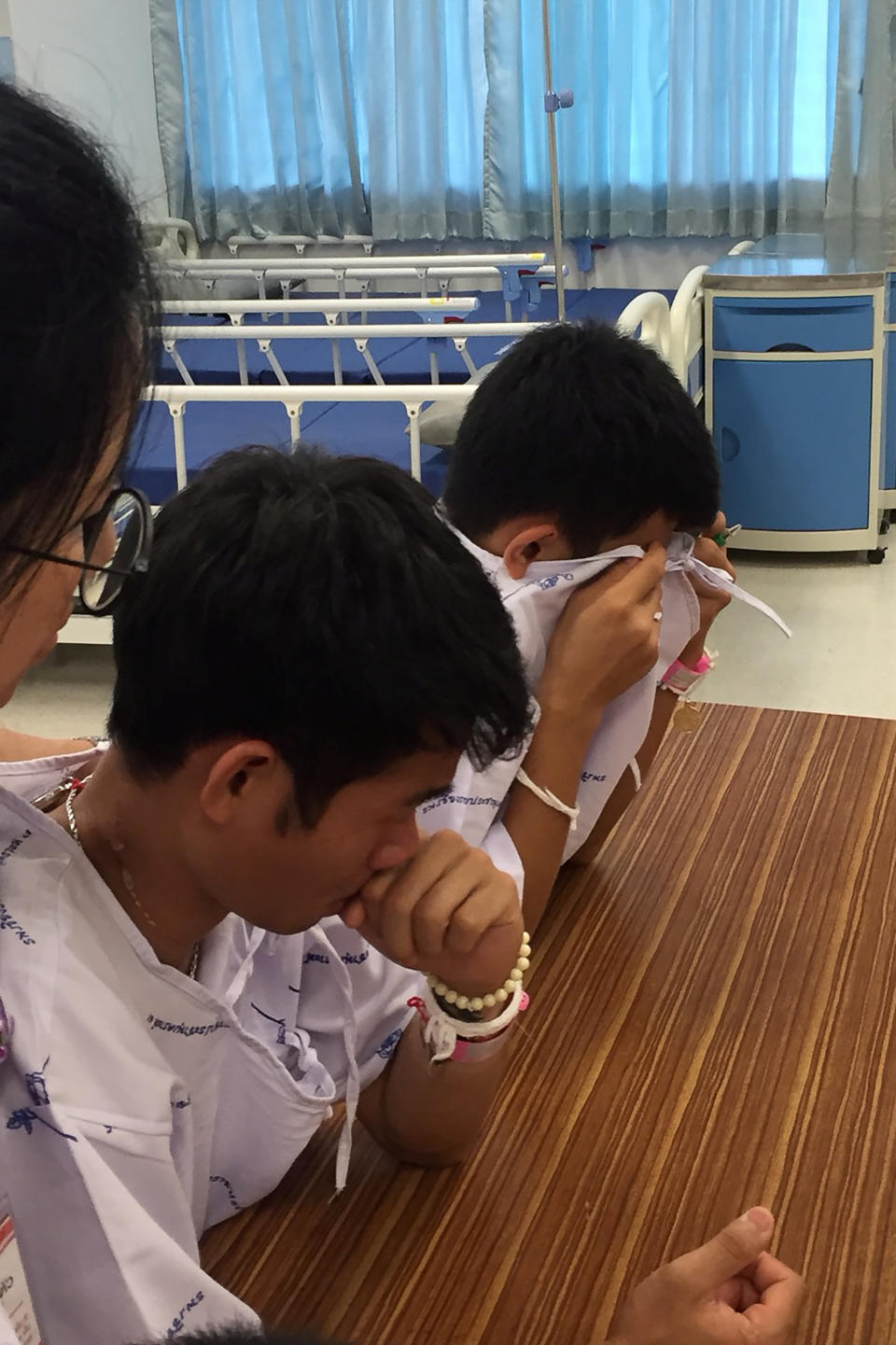 <em>Members of the ‘Wild Boars’ soccer team and their coach cry after writing messages on a drawing of Kunan (Reuters)</em>