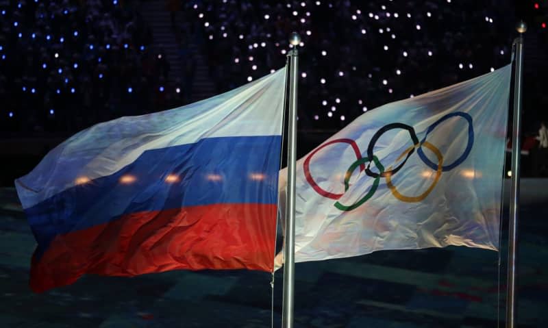 The Olympic flag (R) and the Russian flag flutter during the Closing Ceremony of the 2014 Sochi Winter Games at the Fisht Stadium. Kay Nietfeld/dpa