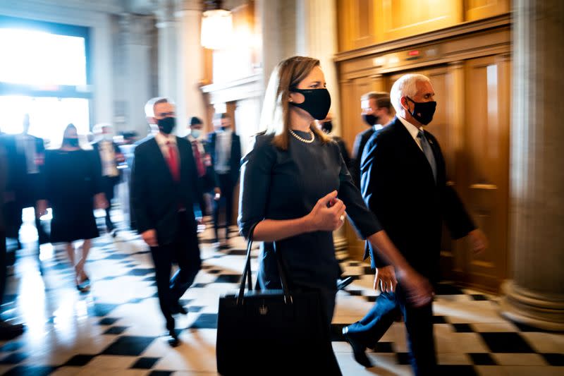 Judge Amy Coney Barrett and U.S. Vice President Mike Pence walk through the Capitol to meet with Senators, in Washington