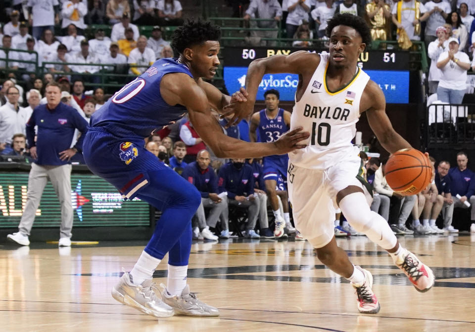 FILE - Baylor guard Adam Flagler (10) dribbles past Kansas guard Ochai Agbaji (30) during an NCAA college basketball game Feb. 26, 2022, in Waco, Texas. While Baylor returns only two starters – Flagler and big man Flo Thamba – the roster includes two guards coming back from injury, two Division I transfers and the league’s top incoming freshman. (AP Photo/Ray Carlin, File)