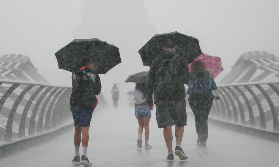 <span>People with umbrellas walk in the rain on the Millennium Bridge in London.</span><span>Photograph: Victoria Jones/PA</span>