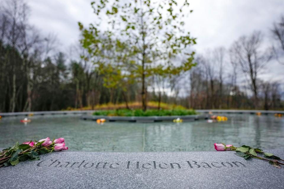 Flowers lay next to the name of Charlotte Bacon, carved in the stone of a memorial dedicated to the victims of the Sandy Hook Elementary School shooting, in Newtown, Conn., Sunday, Nov. 13, 2022. (AP Photo/Bryan Woolston)