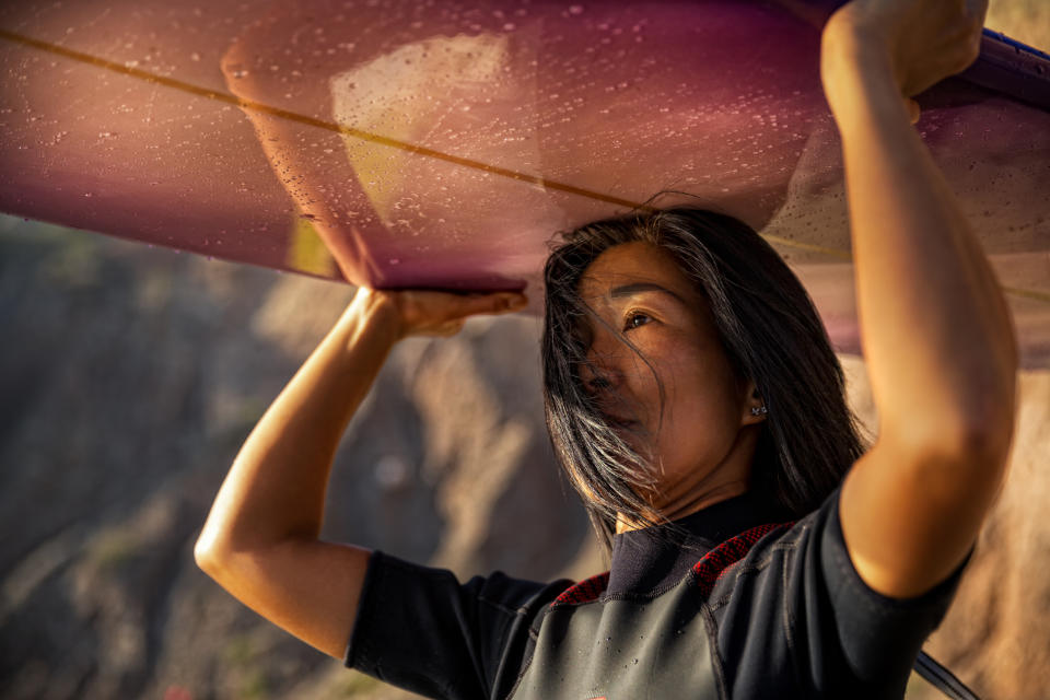 Woman lifts a kayak overhead, emphasizing strength and outdoor family activities