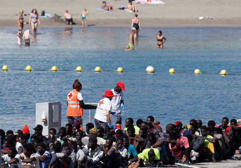 A group of migrants is assisted by Red Cross personnel after arriving to the port of Los Cristianos on a wooden boat