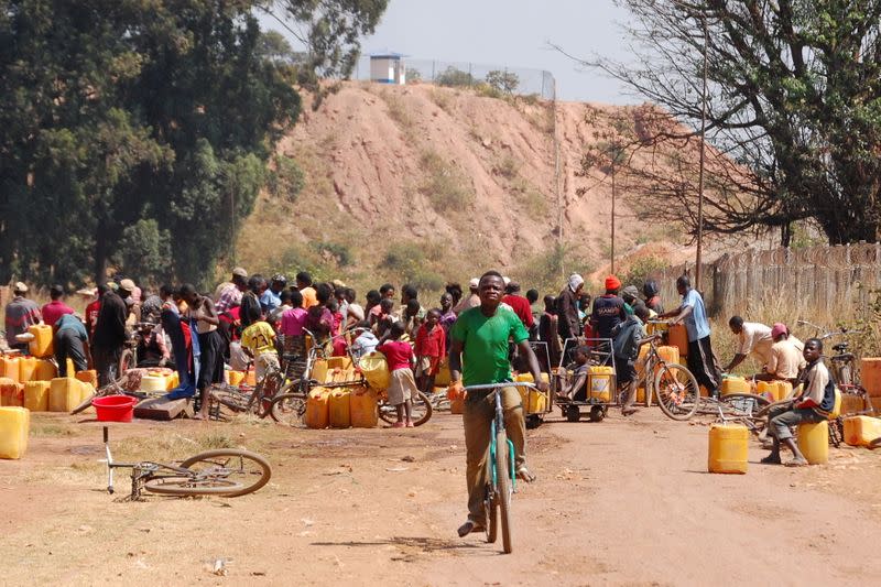 FILE PHOTO: People fetch water outside a copper and cobalt mine run by Sicomines in Kolwezi