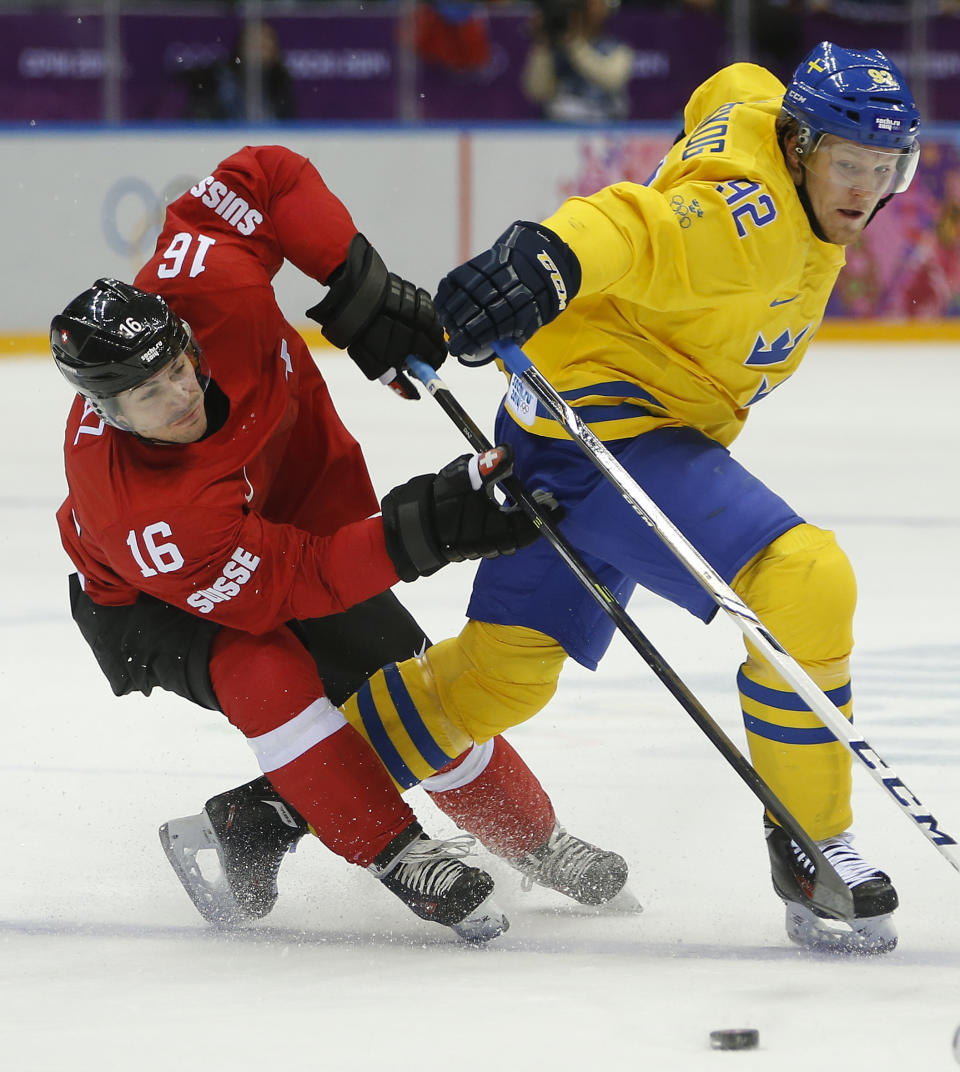 Switzerland defenseman Raphael Diaz fights for the puck against Sweden forward Gabriel Landeskog in the first period of a men's ice hockey game at the 2014 Winter Olympics, Friday, Feb. 14, 2014, in Sochi, Russia. (AP Photo/Mark Humphrey)