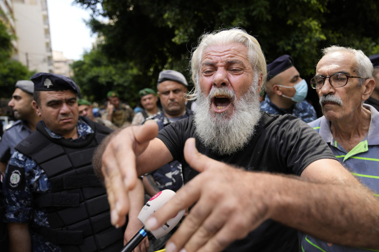 A man shouts as he protests against banks outside a bank where another armed man holds hostages in Beirut, Lebanon, Thursday, Aug. 11, 2022. A Lebanese security official says a man armed with a shotgun has broken into a Beirut bank, holding employees hostage and threatening to set himself ablaze with gasoline unless he receives his trapped saving. (AP Photo/Hussein Malla)