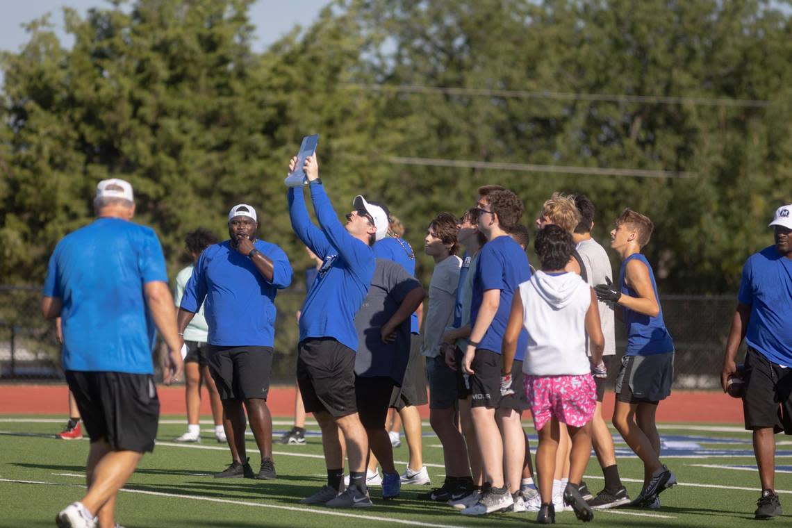 The team huddles to review a play during freshman football camp at Midlothian High School on Thursday, July 28, 2022.