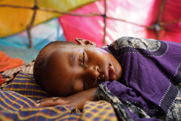 <p>Covered in flies, a young Somali IDP boy sleeps in the family shelter at a makeshift camp in central Mogadishu. (Photo: Giles Clarke/Getty Images) </p>