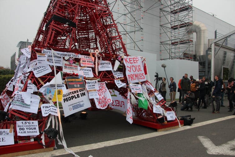Protest signs against fossil fuels cover a red pylon