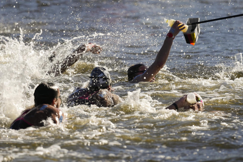 Swimmers grab a bottle at a feeding station during the men's marathon swimming event at the 2020 Summer Olympics, Thursday, Aug. 5, 2021, in Tokyo, Japan. (AP Photo/Jae C. Hong)