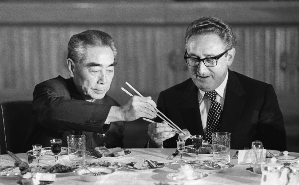 U.S. Secretary of State Henry Kissinger accepts food from Chinese Premier Zhou Enlai during a state banquet in the Great Hall of the People in Beijing.