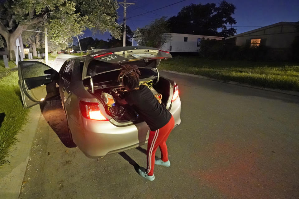 Jada Riley goes through her possessions in the trunk of her car near her former apartment, Thursday, July 28, 2022, in New Orleans. Two months behind on rent, Riley made the difficult decision last month to leave her apartment rather than risk an eviction judgment on her record. Now, she's living in her car with her 6-year-old son, sometimes spending nights at the apartments of friends or her son's father. (AP Photo/Gerald Herbert)