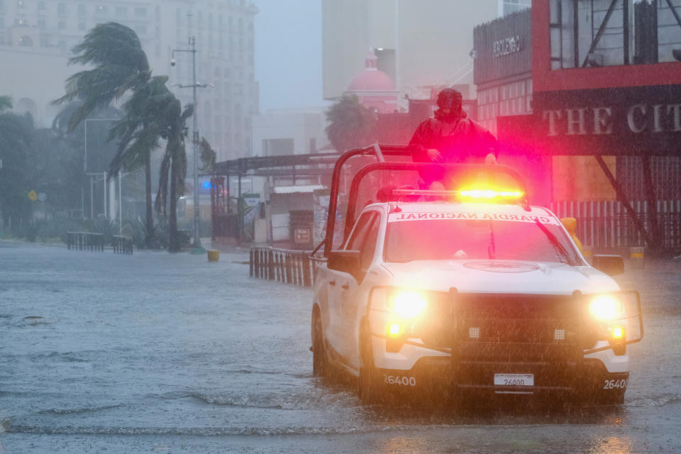 Miembros de la Guardia Nacional patrullan a través de una calle inundada, durante los fuertes vientos y lluvias causados ​​por el huracán Beryl, una tormenta de categoría 2, en Cancún, México, el 5 de julio de 2024. REUTERS/Paola Chiomante