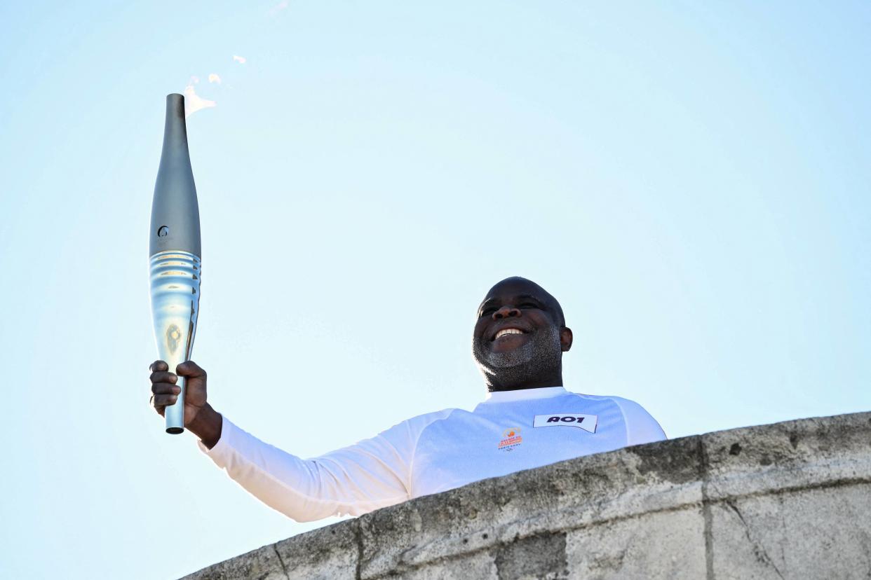 Basile Boli, premier porteur du relais de la flamme olympique, ici devant la Basilique Notre-Dame de la Garde à Marseille, le 8 mai 2024.