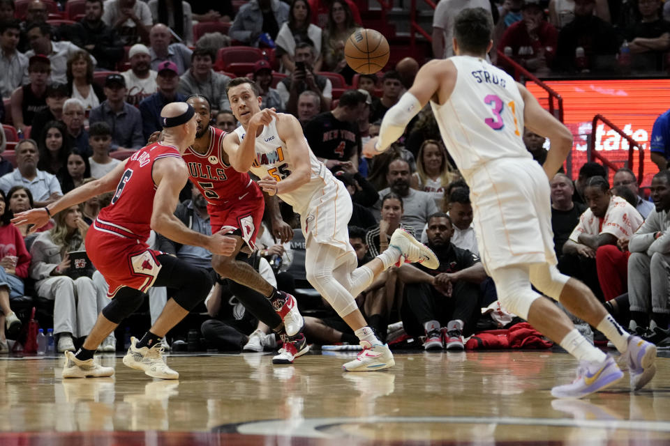 Miami Heat forward Duncan Robinson, center, passes the ball to guard Max Strus (31) as Chicago Bulls guard Alex Caruso (6) defends during the first half of an NBA basketball game, Tuesday, Dec. 20, 2022, in Miami. (AP Photo/Lynne Sladky)