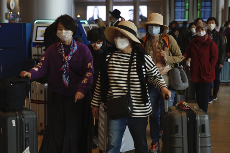 <span class="caption">Tourists wearing protective masks from Korea walk through Ben Gurion Airport near Tel Aviv, Israel.</span> <span class="attribution"><a class="link " href="http://www.apimages.com/metadata/Index/Israel-Coronavirus-Outbreak/10dd39c16da343cd9277b75fbd6b8408/1/0" rel="nofollow noopener" target="_blank" data-ylk="slk:AP Photo / Ariel Schalit;elm:context_link;itc:0;sec:content-canvas">AP Photo / Ariel Schalit</a></span>