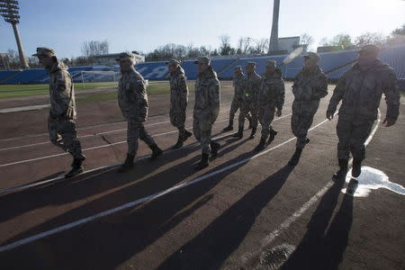 Members of the People's Militia of Crimea walk near the pitch after a soccer match in Simferopol, Crimea, in this March 14, 2015 file photo. REUTERS/Maxim Shemetov/Files