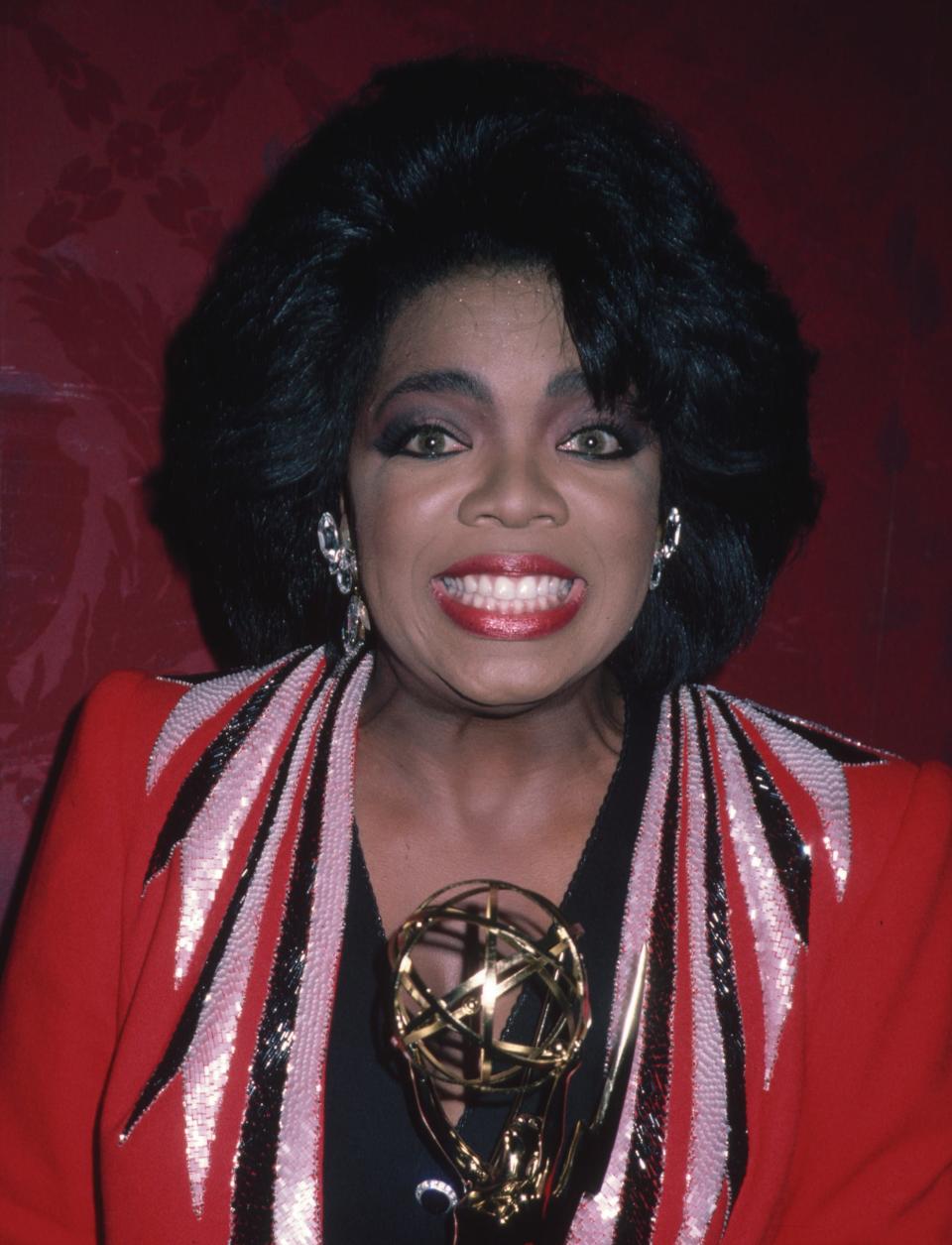 Oprah smiling while holding an award
